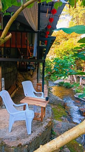 two white chairs and a table next to a river at mae oui next to the water&แม่อุ๊ยที่พักติดน้ำ in Ban Pok Nai
