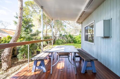 a picnic table on the porch of a house at Cosy Getaway with Fireplace and Spacious Backyard in Broulee