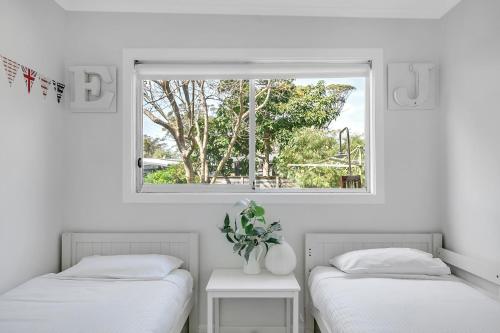 two beds in a room with a window at Cosy Getaway with Fireplace and Spacious Backyard in Broulee