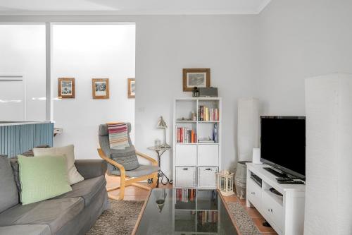 a living room with a couch and a tv at Cosy Getaway with Fireplace and Spacious Backyard in Broulee