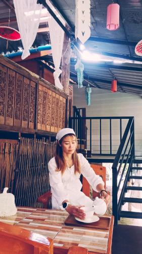 a woman sitting at a table with plates at mae oui next to the water&แม่อุ๊ยที่พักติดน้ำ in Ban Pok Nai
