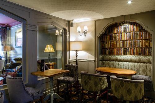 a library with tables and chairs and a book shelf with books at Best Western Lichfield City Centre The George Hotel in Lichfield
