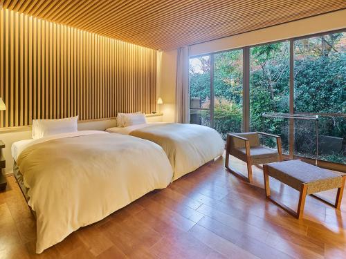 a bedroom with two beds and a large window at Chikurakutei in Minami Aso