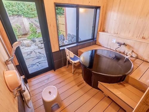 a bathroom with a large tub and a window at Chikurakutei in Minami Aso