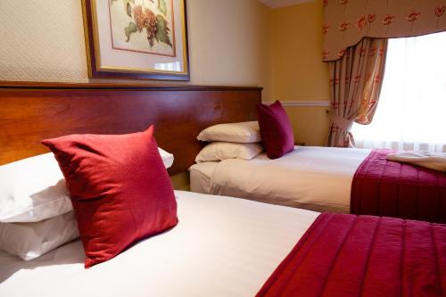 a hotel room with two beds with red pillows at Best Western Lichfield City Centre The George Hotel in Lichfield