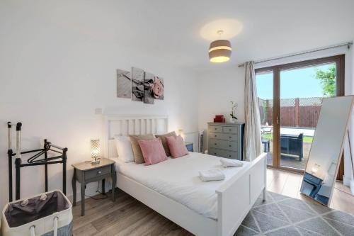 a white bedroom with a bed and a window at Multiple 2-Bedroom Apartments near Harry Potter Studios - 2-Minute walk to Bushey Station - 20 Minutes to London Euston - Ideal for Families & Business - Free Parking in Watford