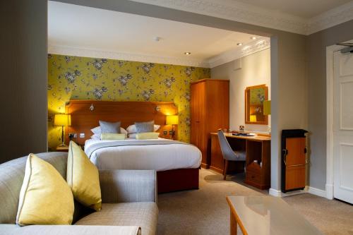 a hotel room with a bed and a desk at Best Western Lichfield City Centre The George Hotel in Lichfield