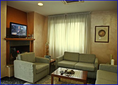 a living room with a couch and chairs and a tv at Hotel Meeting in Ciampino