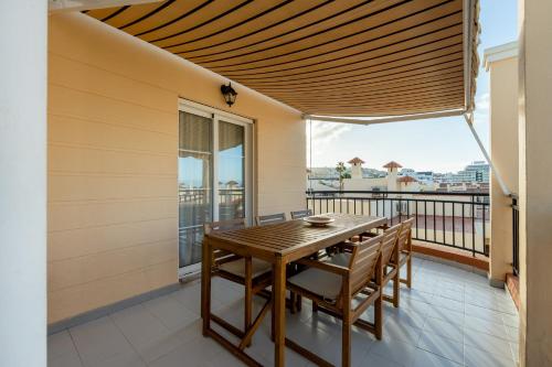 a porch with a wooden table and chairs on a balcony at Benny Fañabé - 2 Bed and Loft Apartment, AC, Pool & Parking in Adeje