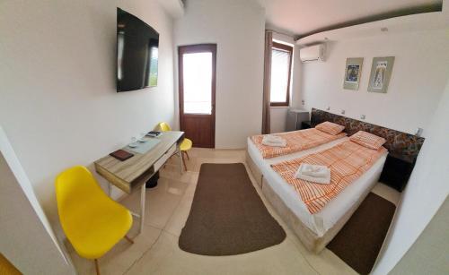 a bedroom with a bed and a table and a yellow chair at Guest House Harmony in Veliko Tŭrnovo