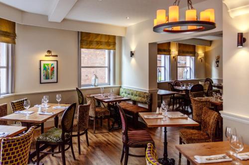 a restaurant with wooden tables and chairs and windows at Best Western Lichfield City Centre The George Hotel in Lichfield