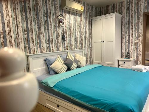 a bedroom with a bed with blue sheets and wallpaper at Rain cha-am by J in Cha Am