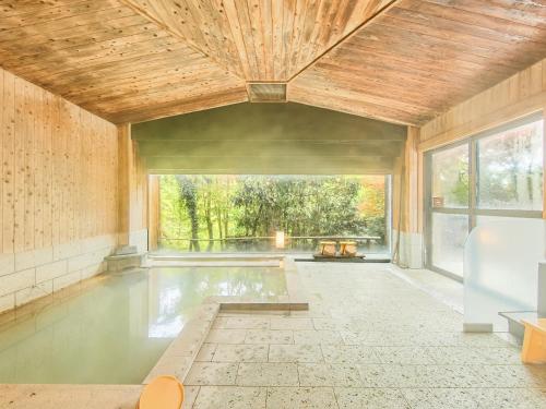 a swimming pool in a room with a large window at Kirishima Momijidani Seiryuso in Kirishima