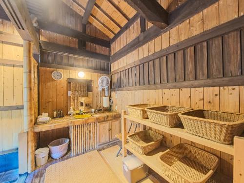 Eine Küche mit Holzwänden und Körben in den Regalen in der Unterkunft Kirishima Momijidani Seiryuso in Kirishima