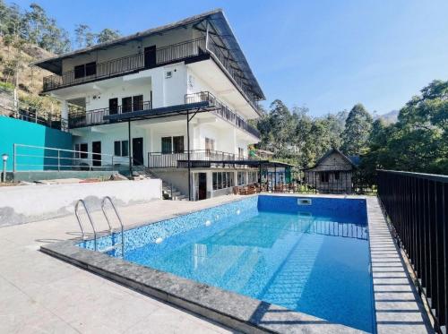 ein Haus mit einem Swimmingpool vor einem Gebäude in der Unterkunft Misty Cloud in Devikolam