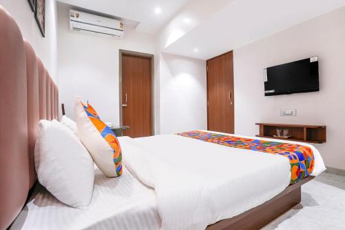 a bedroom with a white bed and a flat screen tv at FabHotel Suruchi Homes in Vasai