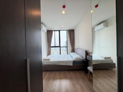 a small bedroom with a bed and a mirror at NUE District Rama 9 Condo in Bangkok
