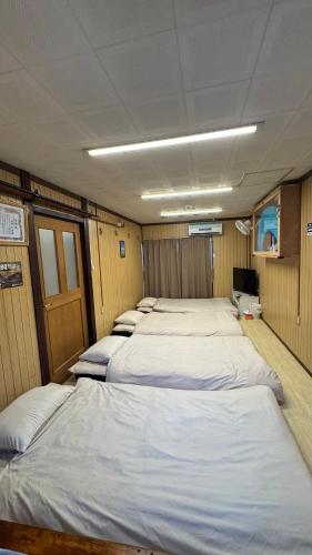 a row of beds lined up in a room at Okinawa Naha JinJin -沖縄伝統体験型宿じんじん- in Naha