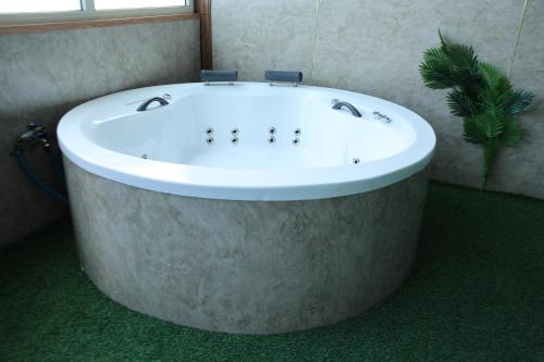 a large bath tub in a bathroom with a window at נוף הכפר - 6 חדרי אירוח לזוגות ומשפחות עם ג'קוזי ובריכה מחוממת משותפים במתחם in Buq‘ātā