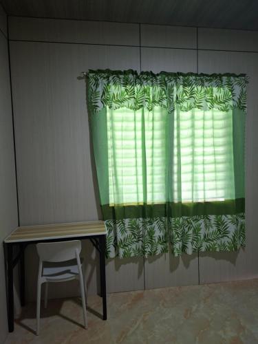 a chair and a window with a green curtain at Nancy's Place in Caniton
