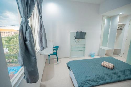 a bedroom with a blue bed and a window at Hotel Pratisarawirya by The Loka in Surabaya