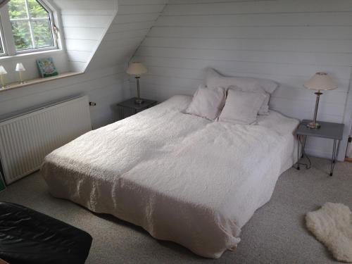 a bedroom with a white bed with two tables and two lamps at Country B&B Horsens in Horsens