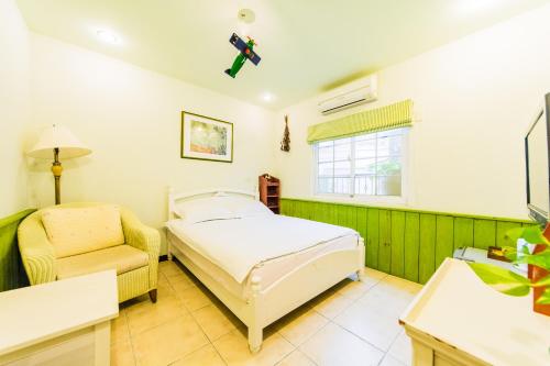 a bedroom with a bed and a chair and a window at Mallorca Homestay in Hualien City