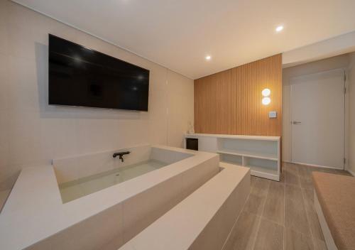 a bathroom with a large tub with a television on the wall at No 25 Iksan Station Branch in Iksan