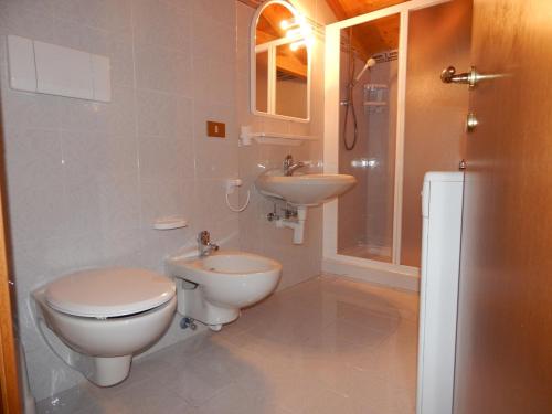 een badkamer met 2 wastafels, een toilet en een douche bij Residence Vittoria in Pinzolo