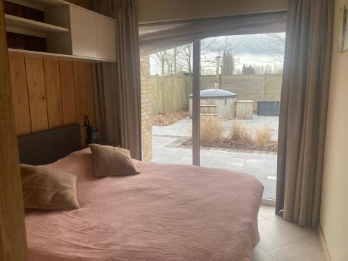 a bedroom with a bed in front of a window at De Notelaar in Alveringem