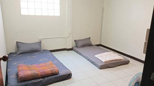two beds in a room with a window at เจแปน บ้านพักรายวัน in Pak Chong