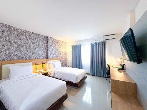 a hotel room with two beds and a flat screen tv at Hotel 88 Batulicin by WH in Batulicin