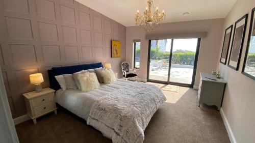 a bedroom with a large bed and a chandelier at Woodcroft in Pwllheli