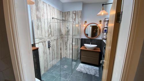 a bathroom with a shower with a sink and a mirror at Woodcroft in Pwllheli