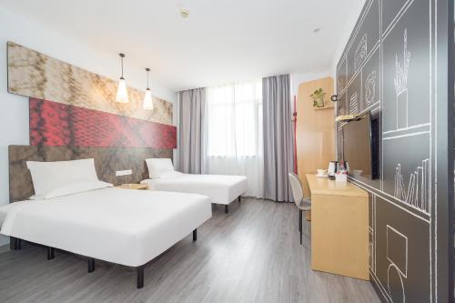 a hotel room with two beds and a desk at Ibis Shanghai Xujiahui in Shanghai