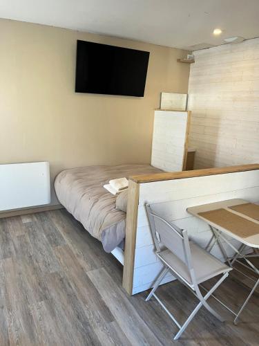La petite cabane في كولون: غرفة بها سرير وطاولة وجهاز تلفزيون