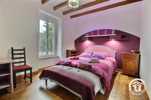 a purple bedroom with a large bed and a chair at Le bois du chat in Plouha