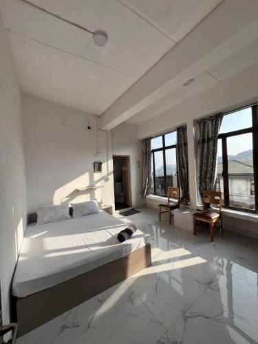 a large white bedroom with a large bed and windows at Aizawl View Hotel in Āīzawl
