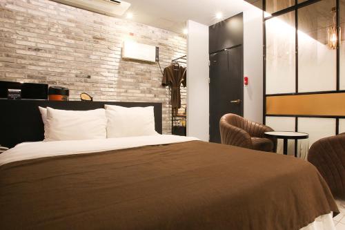 a bedroom with a bed and a brick wall at Hotel Avant in Cheonan