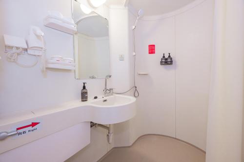 a white bathroom with a sink and a mirror at Ibis Shanghai Xujiahui in Shanghai