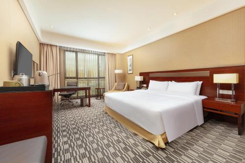 a hotel room with a large white bed and a desk at Four Points by Sheraton Taicang in Taicang