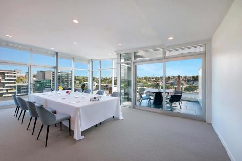 a dining room with a table and chairs and windows at Swiss-Belsuites Victoria Park Auckland in Auckland