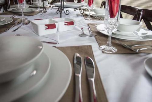 a dining table with white plates and silverware on it at Waves Guest House in Jeffreys Bay