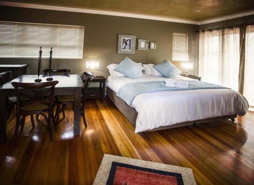 1 dormitorio con cama, mesa y escritorio en Waves Guest House en Jeffreys Bay