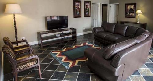 a living room with a leather couch and a television at Waves Guest House in Jeffreys Bay