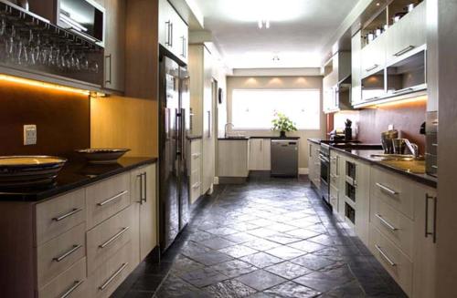 a large kitchen with white cabinets and a tile floor at Waves Guest House in Jeffreys Bay