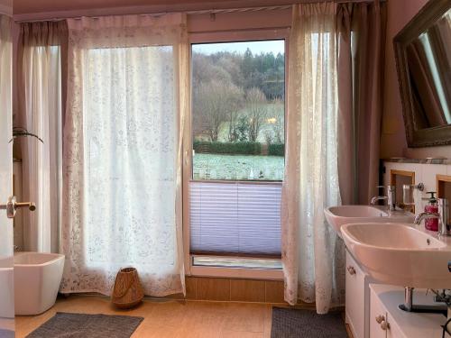 a bathroom with two sinks and a large window at Stilvolle, ruhige Wald-FeWo - Kaminofen, Dachterrasse, hundefreundlich in Remscheid