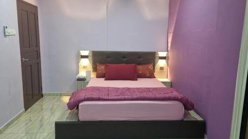 a bedroom with a large bed with purple walls at SriStar in Kluang