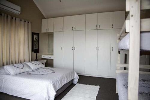 1 dormitorio con 1 cama con armarios blancos y escalera en Twin Okes en Jeffreys Bay