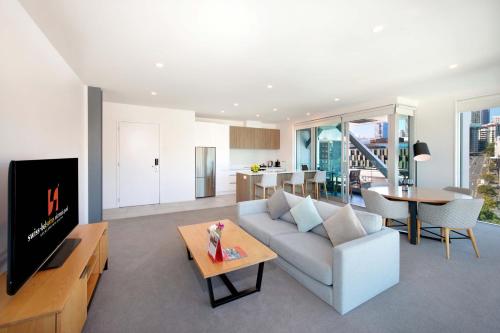 a living room with a couch and a tv at Swiss-Belsuites Victoria Park Auckland in Auckland